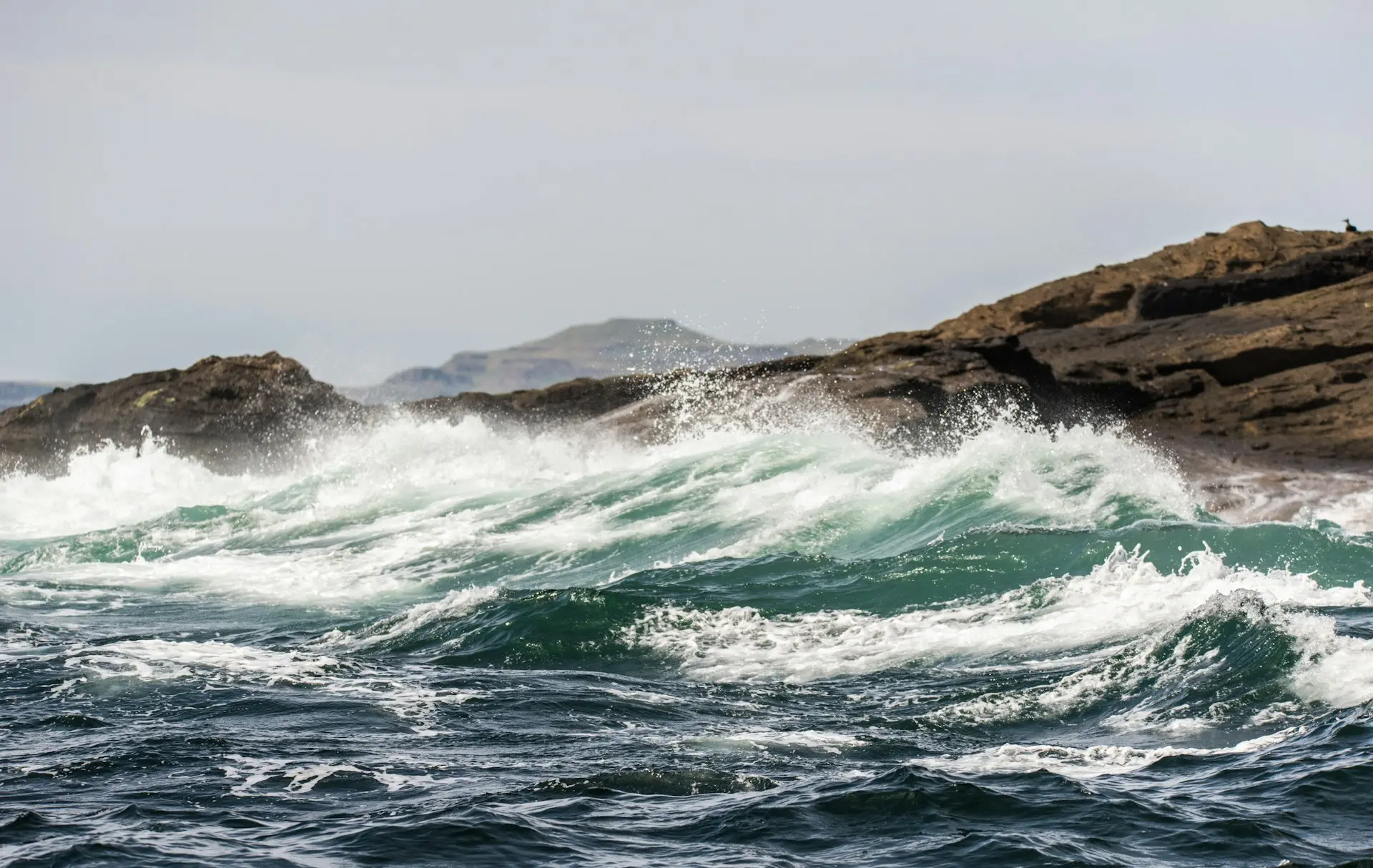 white wave foams breaking on brown rocks in beach