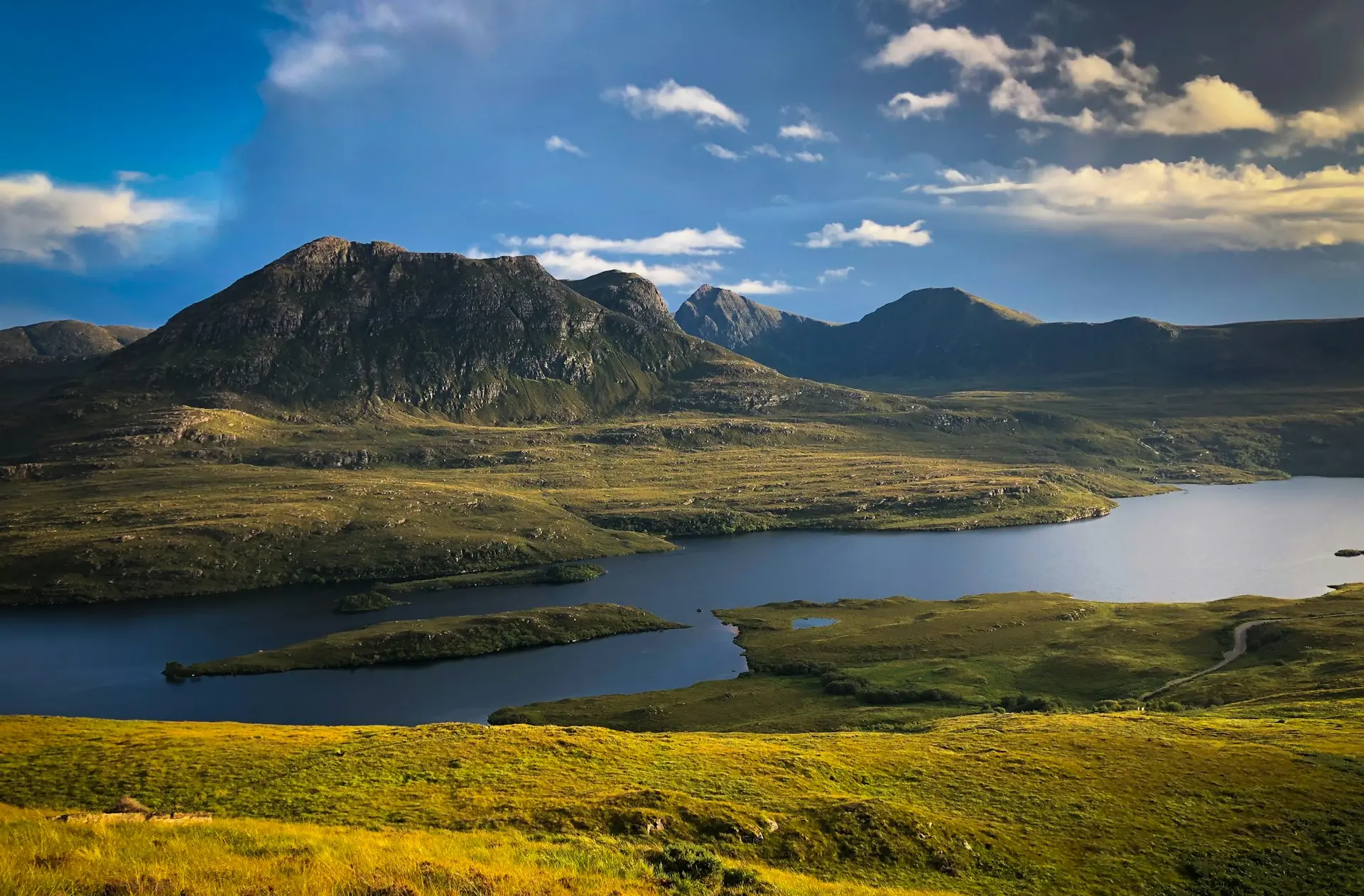 green and brown mountains near body of water under blue sky during daytime