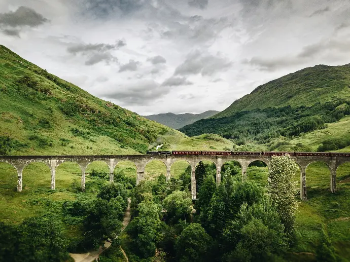 train passing by bridge over mountains